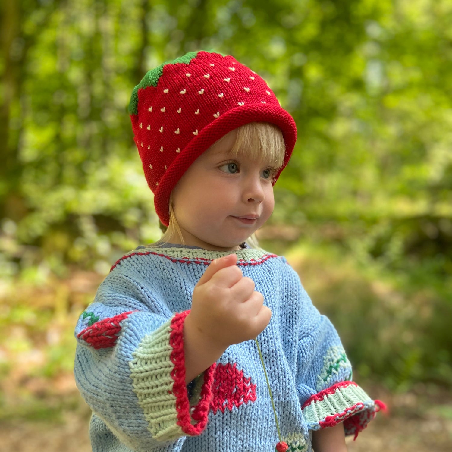 Child wearing a strawberry-themed hat outdoors